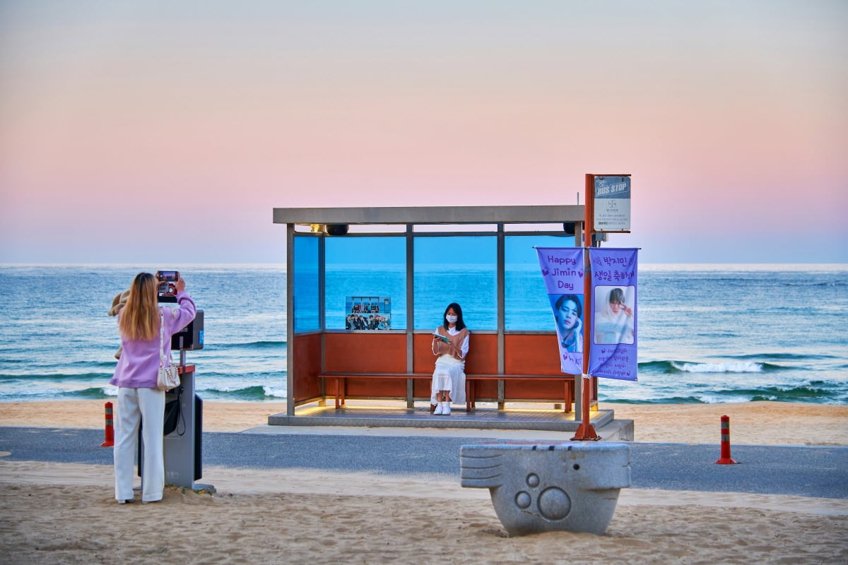 Hyanghohaebyeon Beach in Gangneung with white sand, calm emerald sea, and the rebuilt BTS bus stop installed for fans visiting the You Never Walk Alone filming location