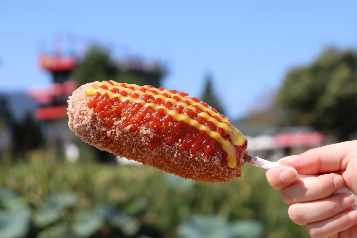 Korean-style hot dog with sauce and sugar on it