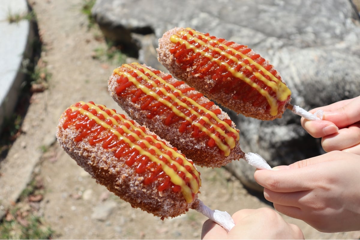 Korean-style hot dog with sauce and sugar on it