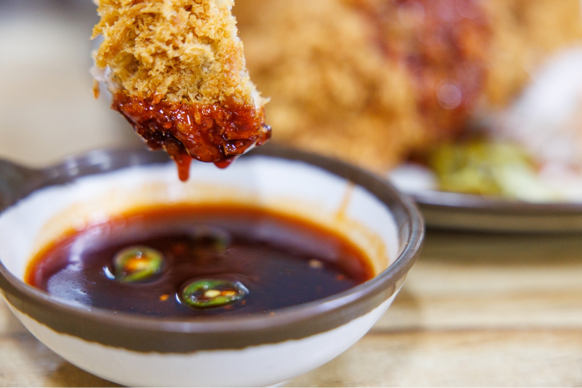A picture of dipping pork cutlet in spicy sauce