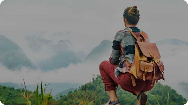 Traveler sits at the edge of the road and looks at a mountain landscape in clouds. Mountains scenic, travel to Asia, summer holiday concept.